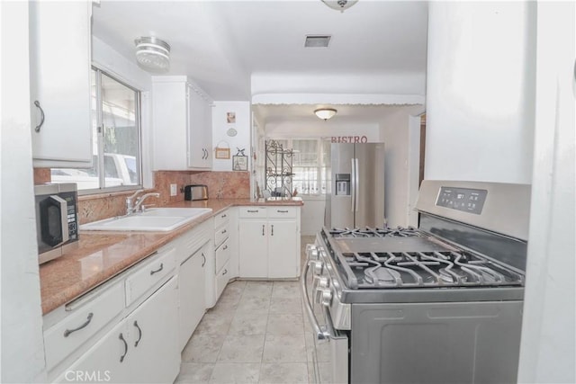 kitchen featuring tasteful backsplash, white cabinetry, appliances with stainless steel finishes, and sink