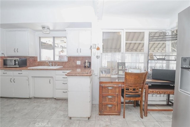 kitchen with white cabinetry, sink, backsplash, and light tile patterned floors