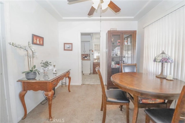 dining area featuring ceiling fan, light colored carpet, and a raised ceiling