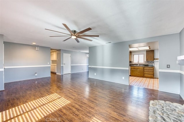 unfurnished living room featuring sink, hardwood / wood-style flooring, and ceiling fan