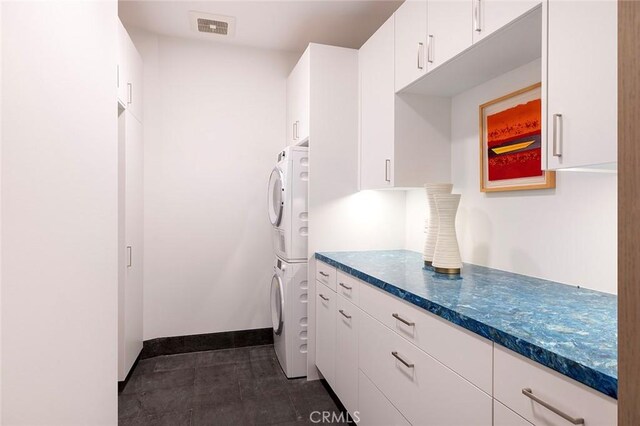 kitchen with white cabinetry and stacked washing maching and dryer