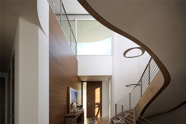 stairs featuring a towering ceiling and wooden walls