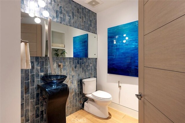 bathroom with wood-type flooring, toilet, tile walls, and vanity