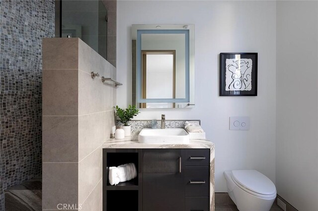 bathroom featuring vanity, toilet, and a tile shower