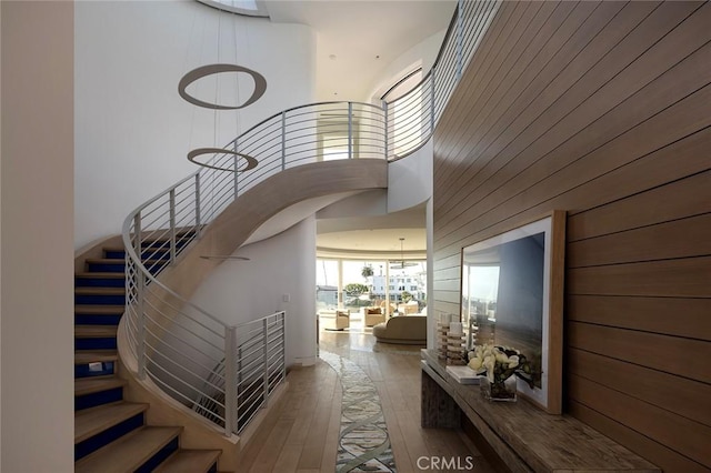 stairs with hardwood / wood-style floors, wooden walls, and a high ceiling