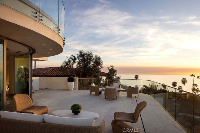 patio terrace at dusk featuring outdoor lounge area and a water view