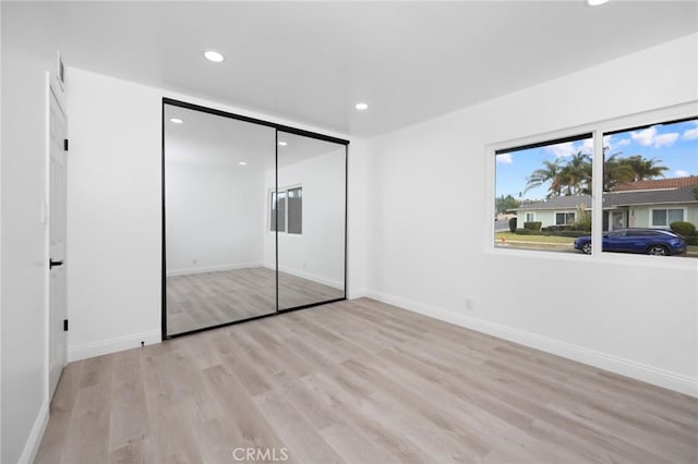 unfurnished bedroom with light wood-type flooring and a closet