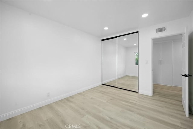 unfurnished bedroom with light hardwood / wood-style flooring and a closet