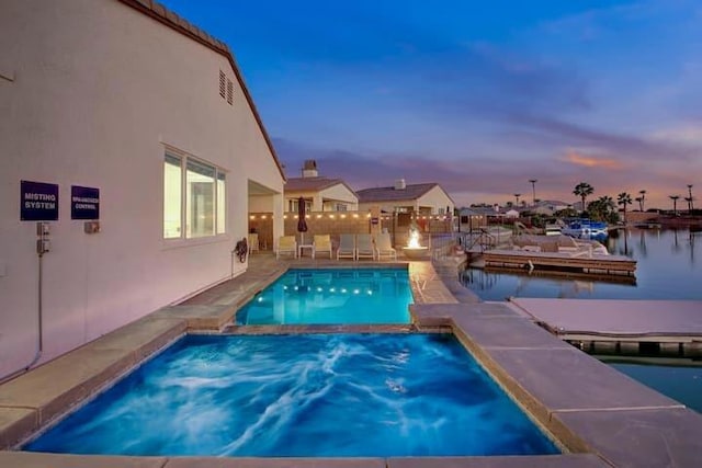 pool at dusk featuring a water view