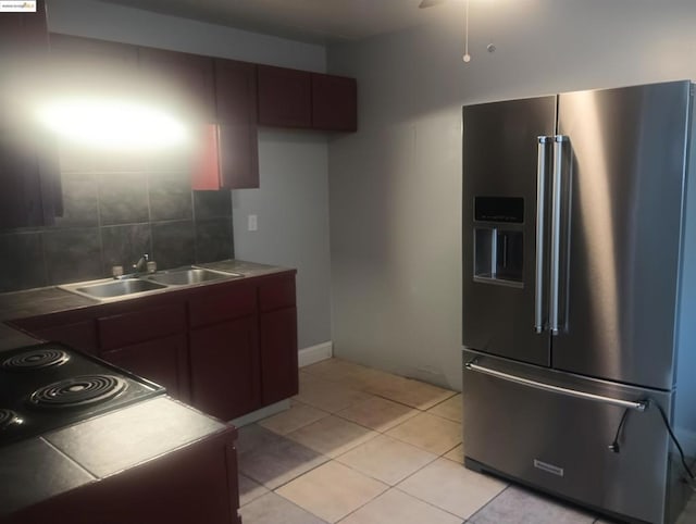 kitchen featuring sink, stovetop, tasteful backsplash, light tile patterned flooring, and high end refrigerator