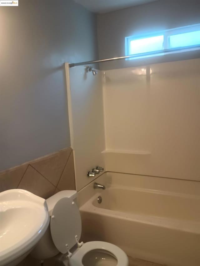 full bathroom featuring washtub / shower combination, toilet, and sink