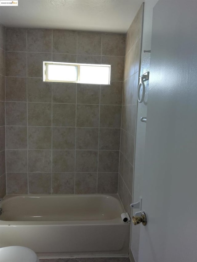 bathroom with toilet and tiled shower / bath