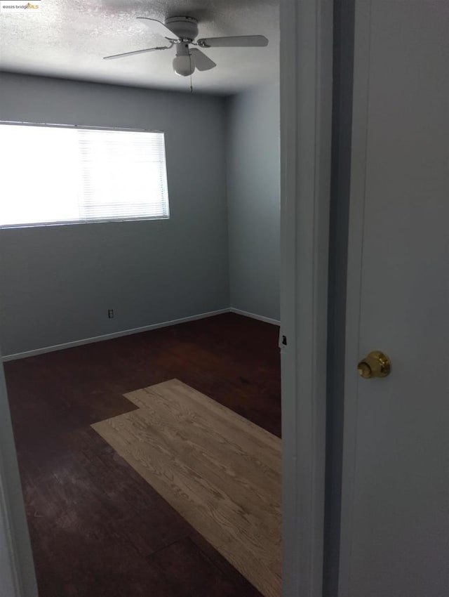 unfurnished room with dark wood-type flooring, ceiling fan, and a textured ceiling