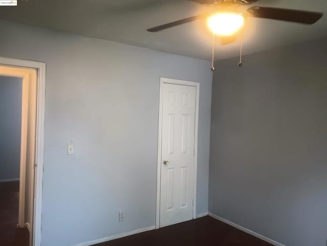 unfurnished room featuring dark wood-type flooring and ceiling fan