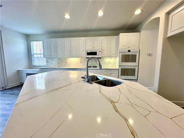 kitchen featuring white appliances, light stone countertops, sink, and decorative backsplash