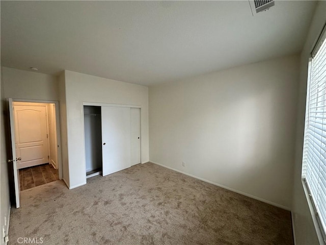 unfurnished bedroom with light carpet and a closet