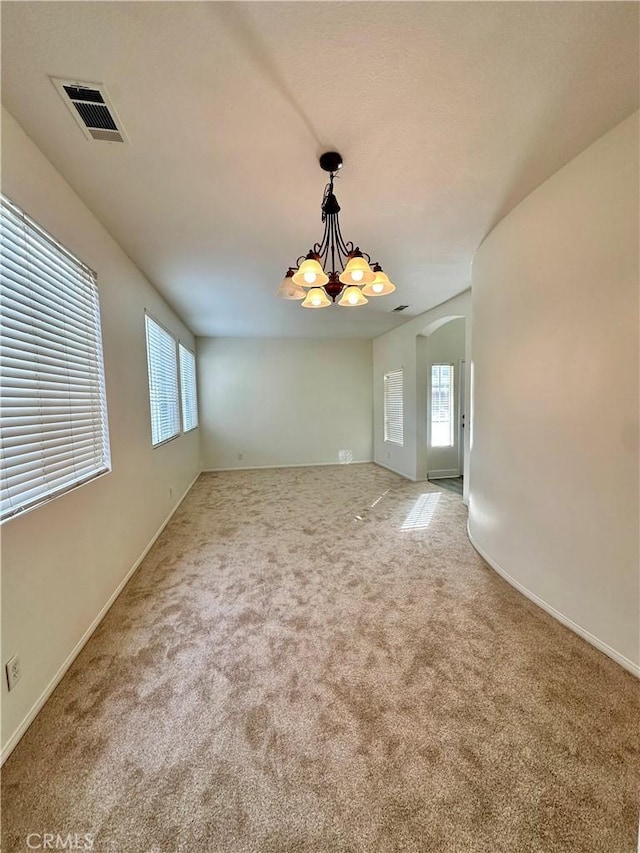 empty room with light carpet and a chandelier