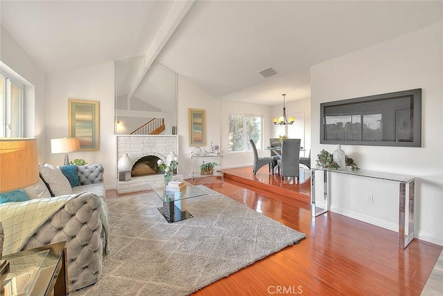 living room featuring a notable chandelier, wood-type flooring, and lofted ceiling with beams