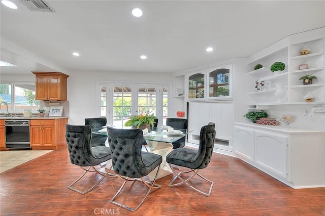 dining room with french doors, sink, and light hardwood / wood-style floors