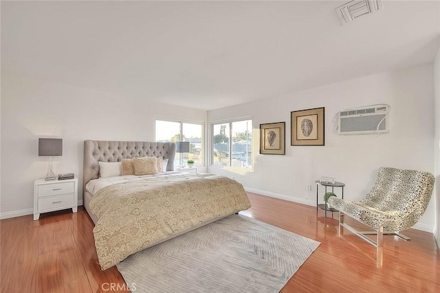 bedroom featuring an AC wall unit and hardwood / wood-style floors