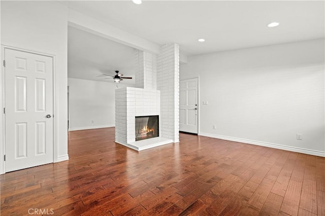 unfurnished living room with beam ceiling, a brick fireplace, hardwood / wood-style flooring, and ceiling fan