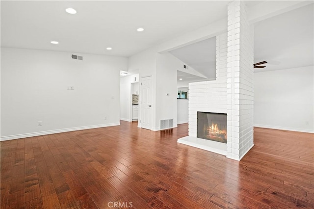 unfurnished living room featuring hardwood / wood-style flooring, lofted ceiling, and a fireplace