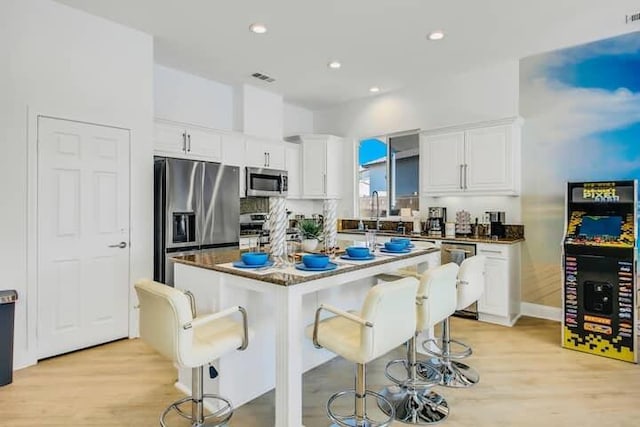 kitchen with stainless steel appliances, a center island, white cabinets, and a breakfast bar