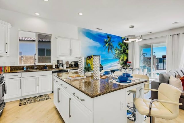 kitchen with dark stone countertops, a center island, sink, and white cabinets