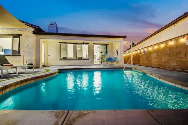 pool at dusk with a patio area