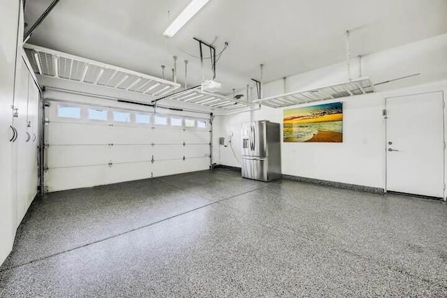 garage with stainless steel refrigerator with ice dispenser and a garage door opener