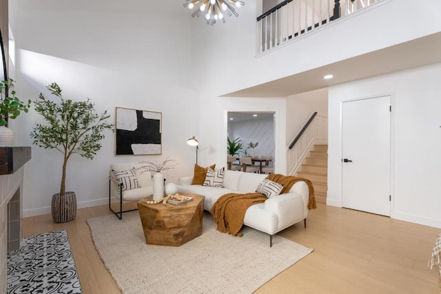 living room with a towering ceiling, a notable chandelier, and light hardwood / wood-style floors