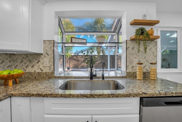 kitchen featuring white cabinetry, stainless steel dishwasher, sink, and light stone counters