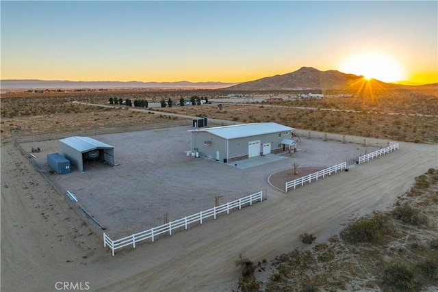 aerial view at dusk featuring a mountain view and a rural view