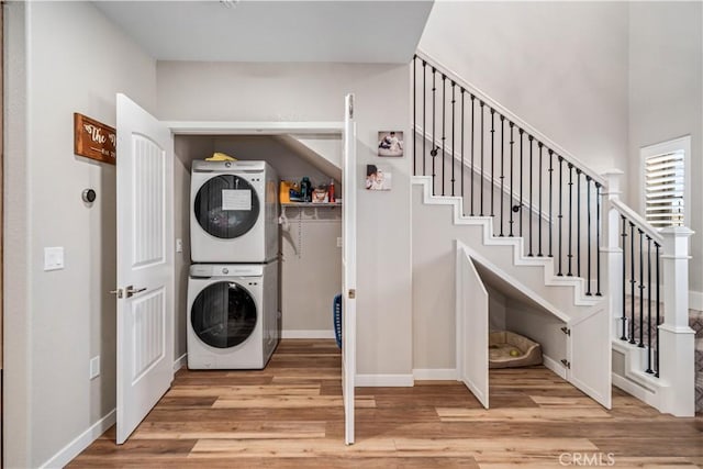 laundry area with light wood-type flooring and stacked washer / dryer