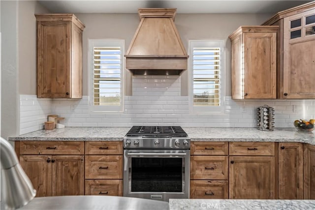 kitchen with tasteful backsplash, a healthy amount of sunlight, custom range hood, and stainless steel range with gas stovetop