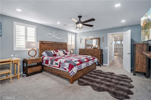 bedroom featuring ceiling fan, light colored carpet, and multiple windows