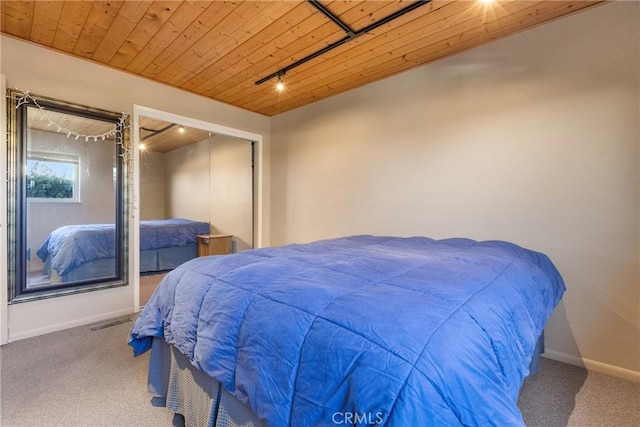 carpeted bedroom with track lighting and wooden ceiling