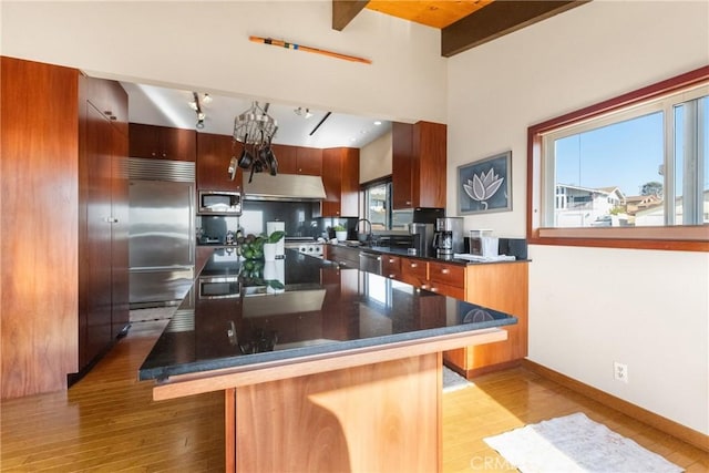 kitchen with a breakfast bar area, built in appliances, light hardwood / wood-style floors, and a kitchen island