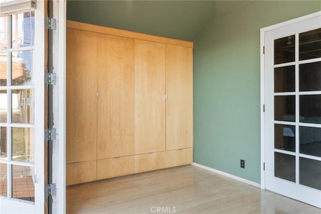 unfurnished bedroom with light hardwood / wood-style flooring and vaulted ceiling