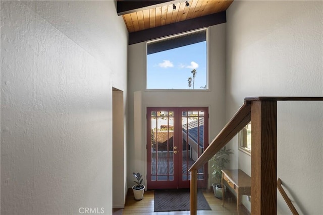 entryway with high vaulted ceiling, hardwood / wood-style flooring, wood ceiling, beam ceiling, and french doors