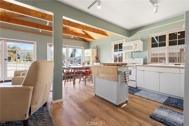 kitchen with white cabinetry, white appliances, a wealth of natural light, and beamed ceiling