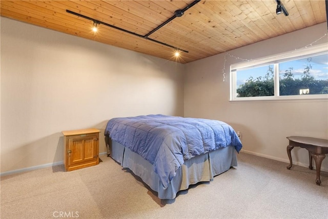 carpeted bedroom with wood ceiling and rail lighting