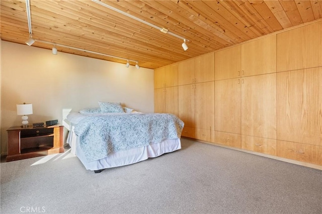 carpeted bedroom with track lighting and wooden ceiling