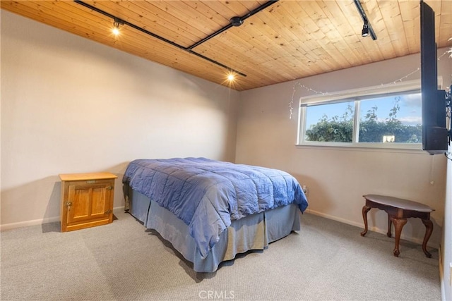 bedroom featuring rail lighting, carpet flooring, and wooden ceiling