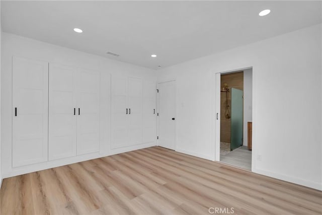 unfurnished bedroom with a closet, light wood-type flooring, and ensuite bath