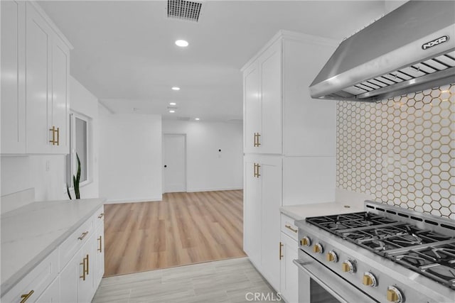 kitchen featuring white cabinetry, backsplash, ventilation hood, and high end stainless steel range oven