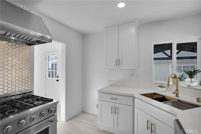 kitchen featuring white cabinetry, stainless steel range with gas cooktop, a wealth of natural light, and wall chimney range hood