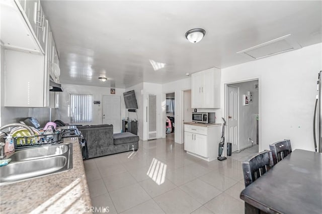 kitchen with light stone countertops, sink, light tile patterned floors, and white cabinets