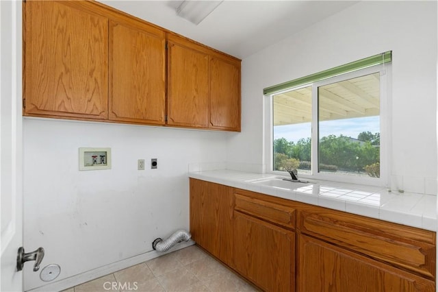 laundry room featuring sink, light tile patterned floors, electric dryer hookup, hookup for a washing machine, and cabinets