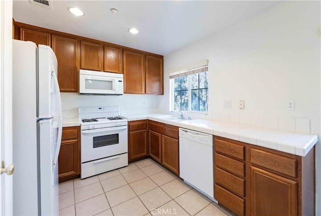 kitchen featuring light tile patterned flooring, sink, tile countertops, and white appliances